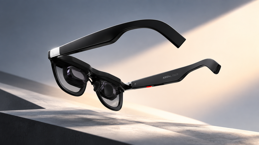 Imagen promocional de unas gafas XREAL One Pro negras, suspendidas sobre una superficie gris, con iluminación cinematográfica y un fondo degradado en tonos gris y crema.
